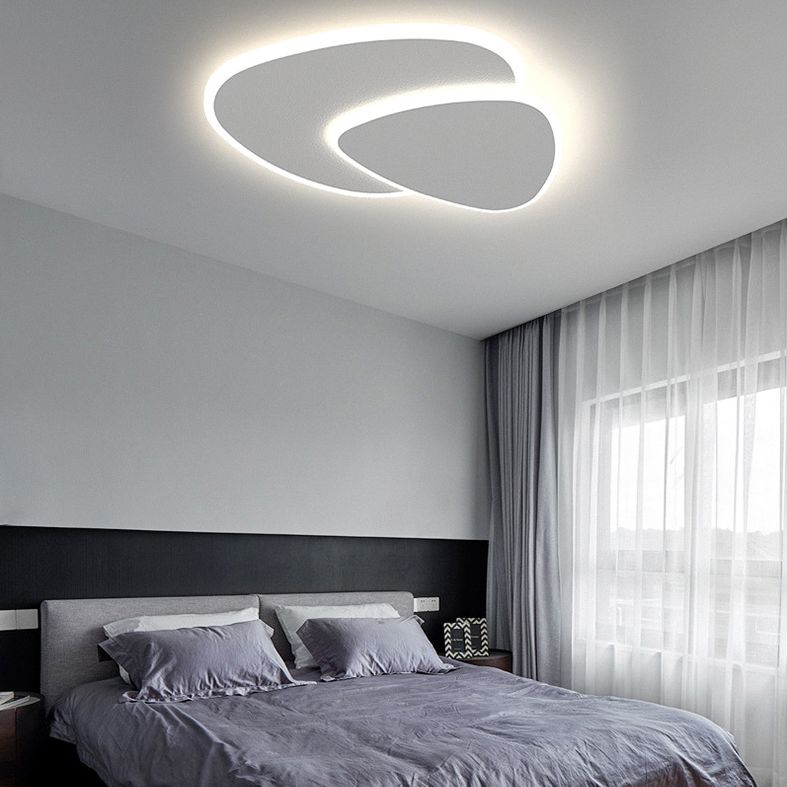 Brindo ceiling light above a bed with grey linen, showing the upward glow across the ceiling