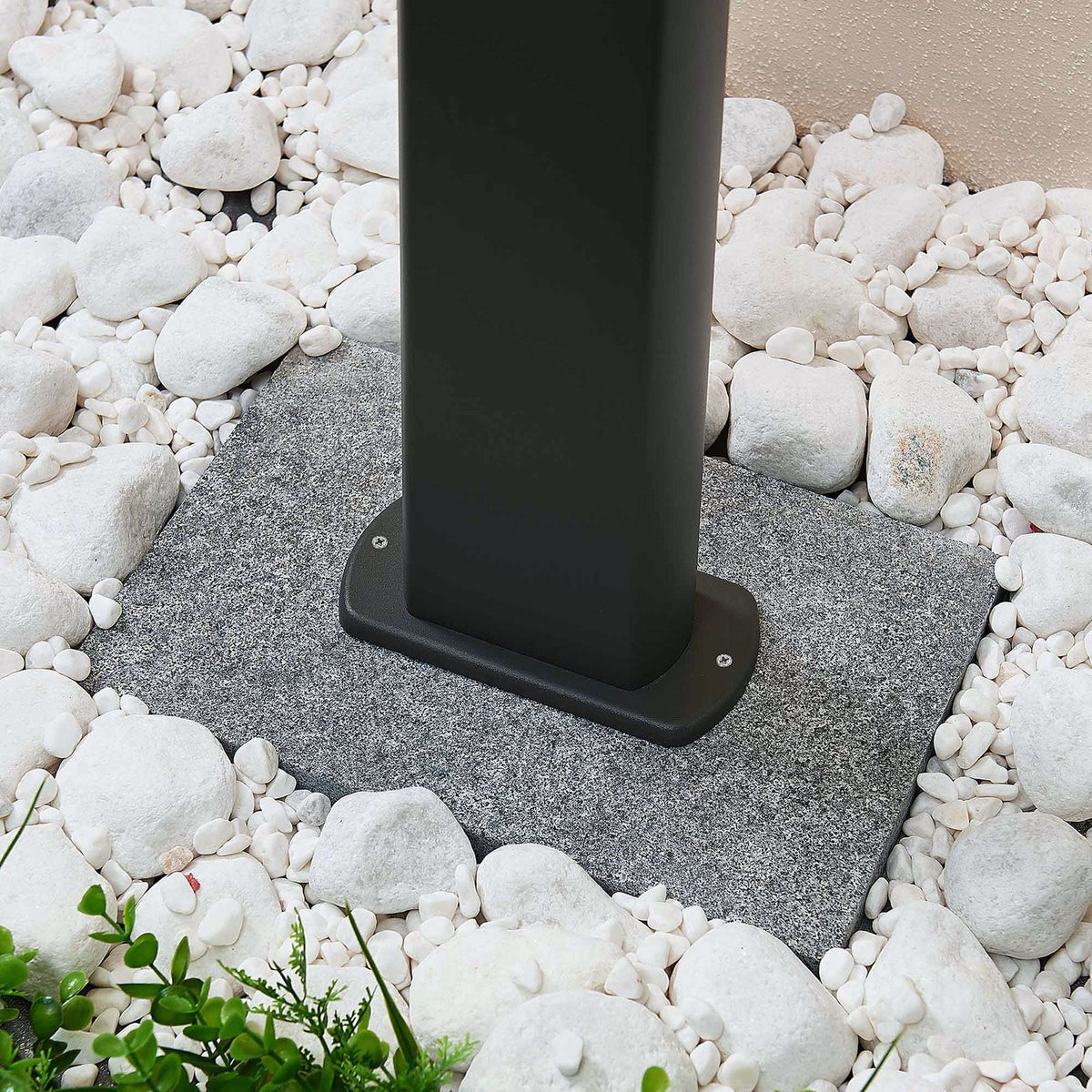 Base of the Mairo path light fixed to a paving slab surrounded by white garden pebbles