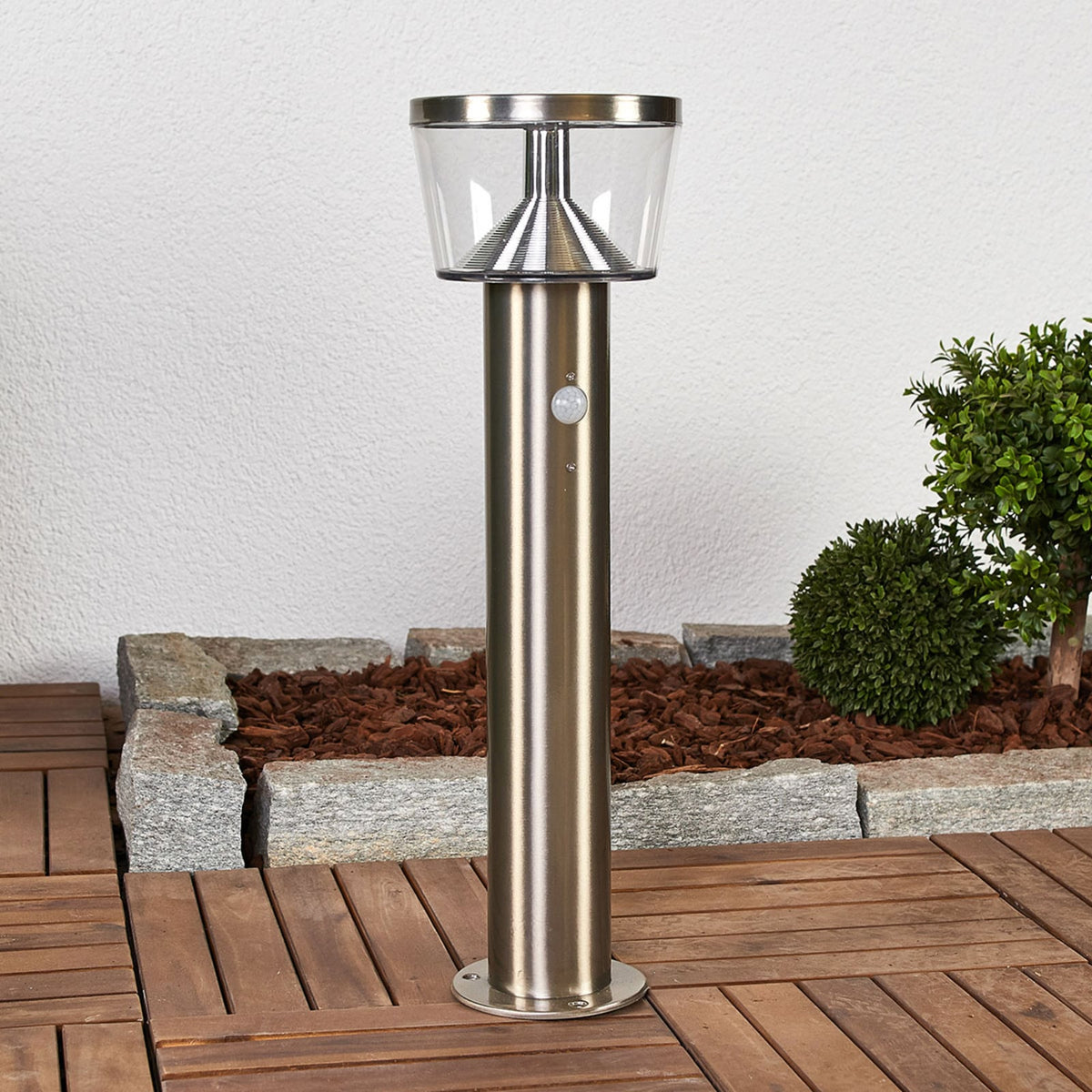 Anjo Solar Pedestal Light installed on decking beside a planted border