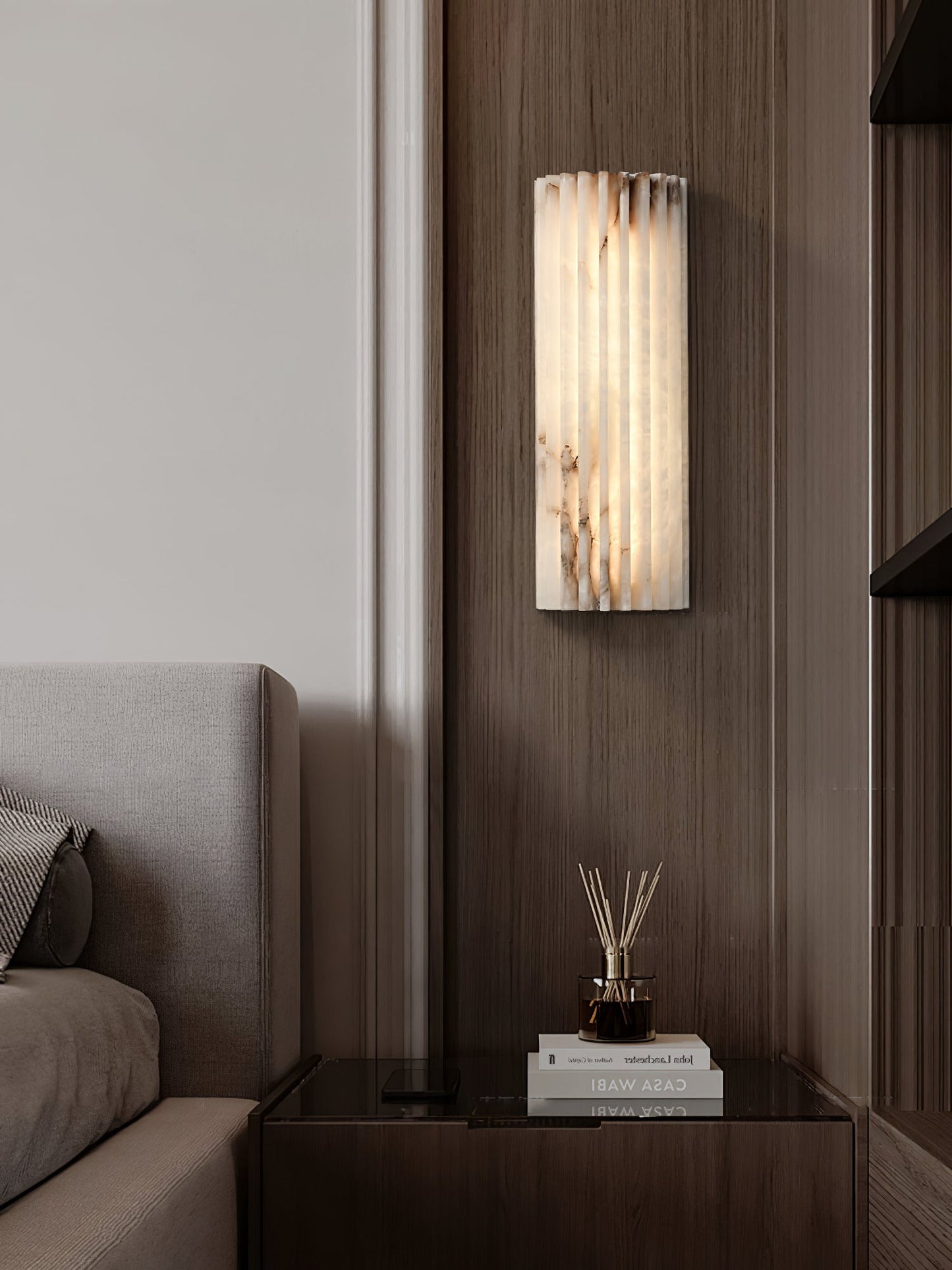Alcaro alabaster wall light mounted on a dark walnut panelled wall beside a sofa