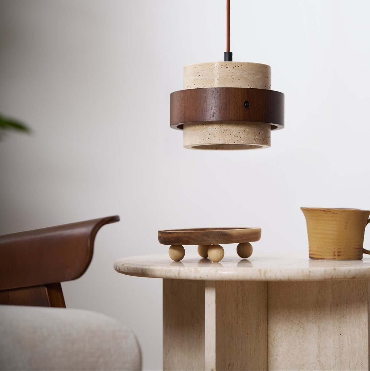 Cavora travertine pendant light above a round stone table in a dining space