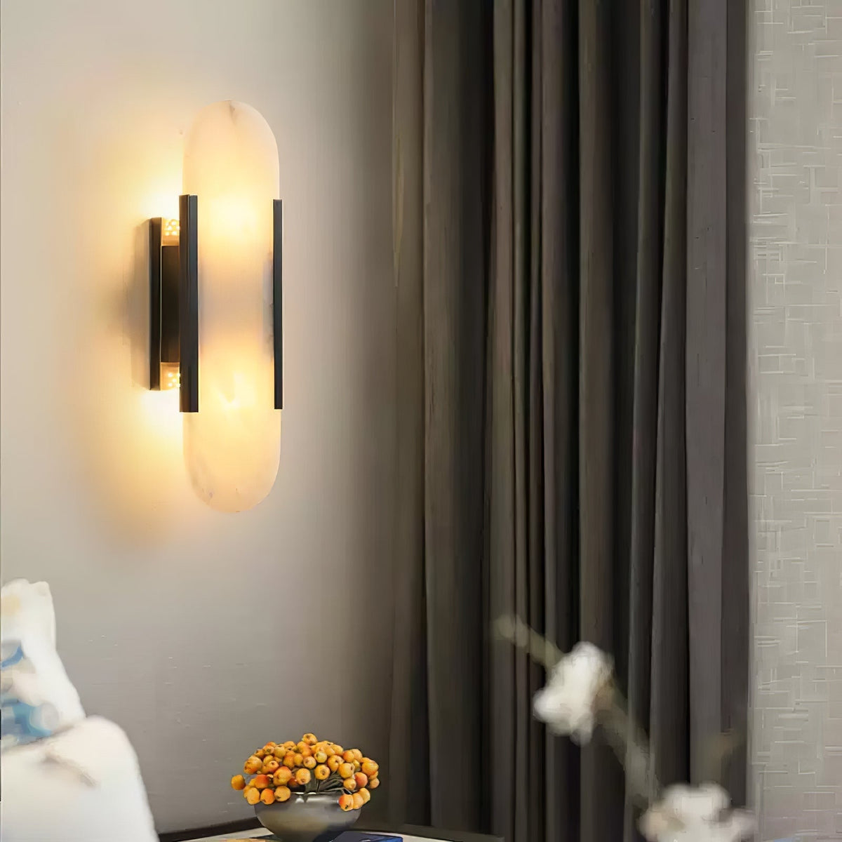 Veola alabaster wall light mounted in a bedroom beside curtains, glowing warm