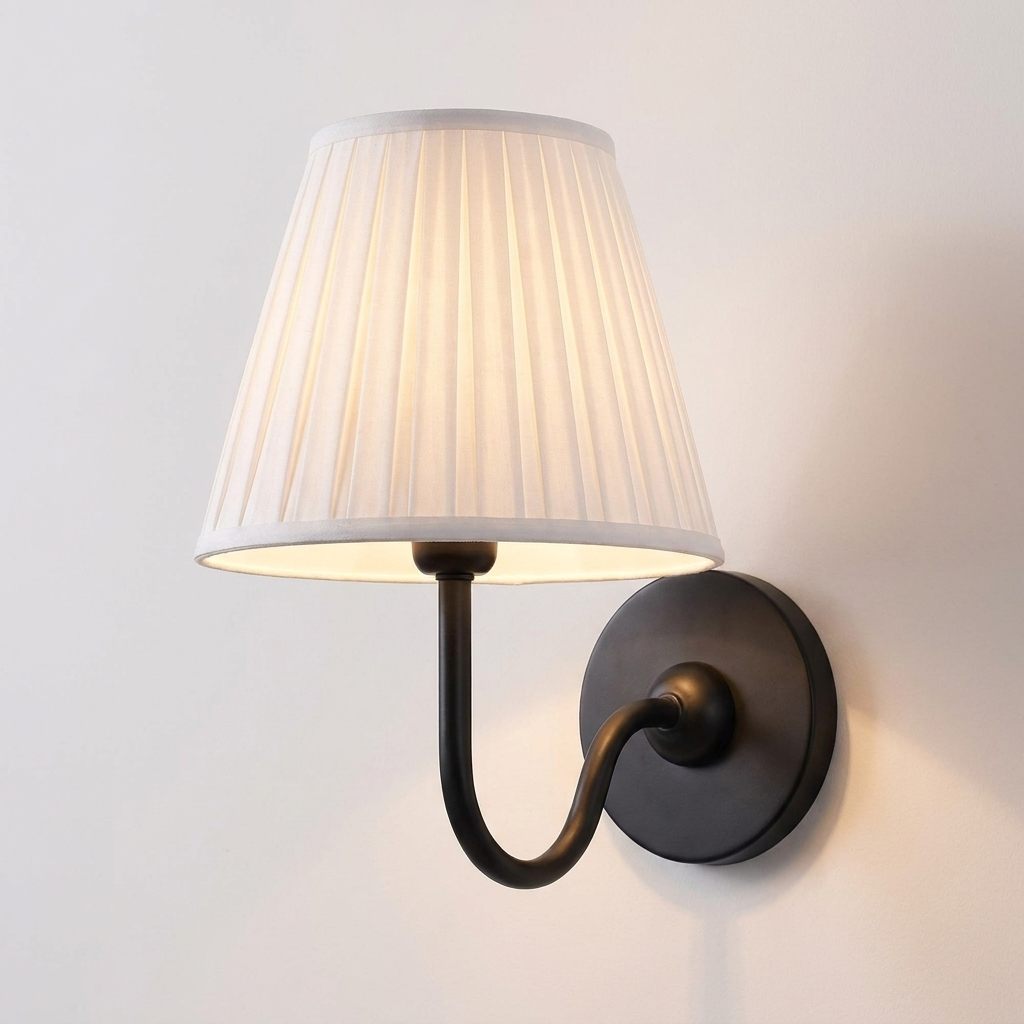 Close view of the pleated white shade and matte black curved arm on the Nora wall light