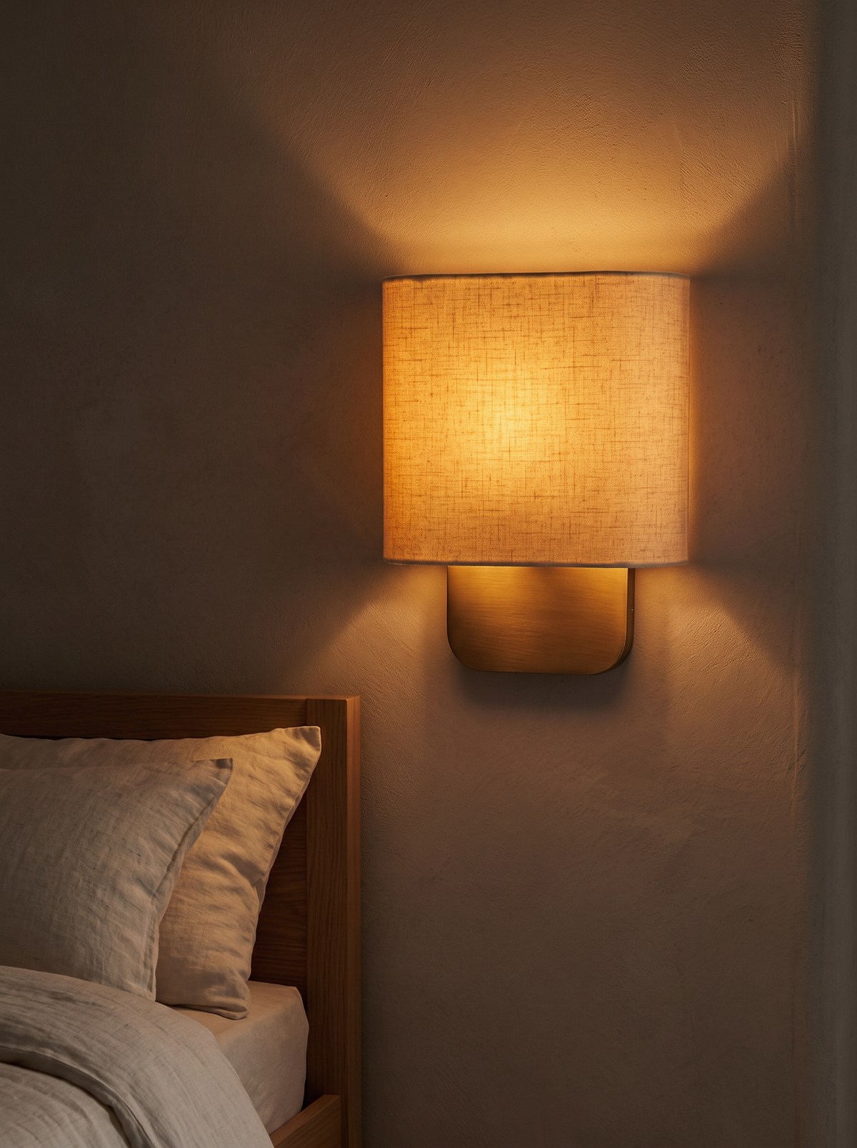 Lino Curved Linen Wall Light - evening bedroom glow, linen shade lit amber at 2700K beside oak bed