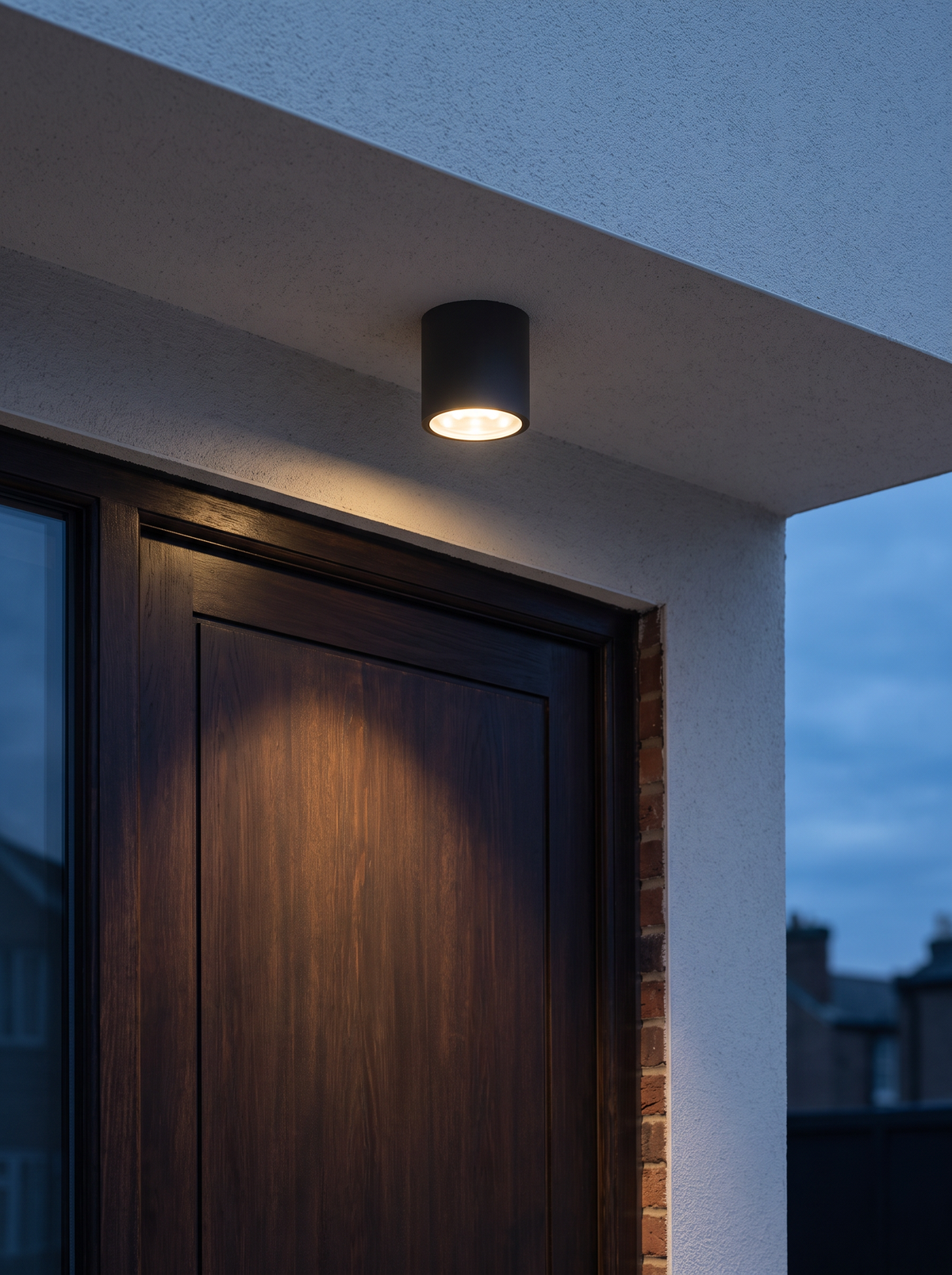 Mero Round Outdoor Ceiling Light - mounted on render soffit above front door at dusk