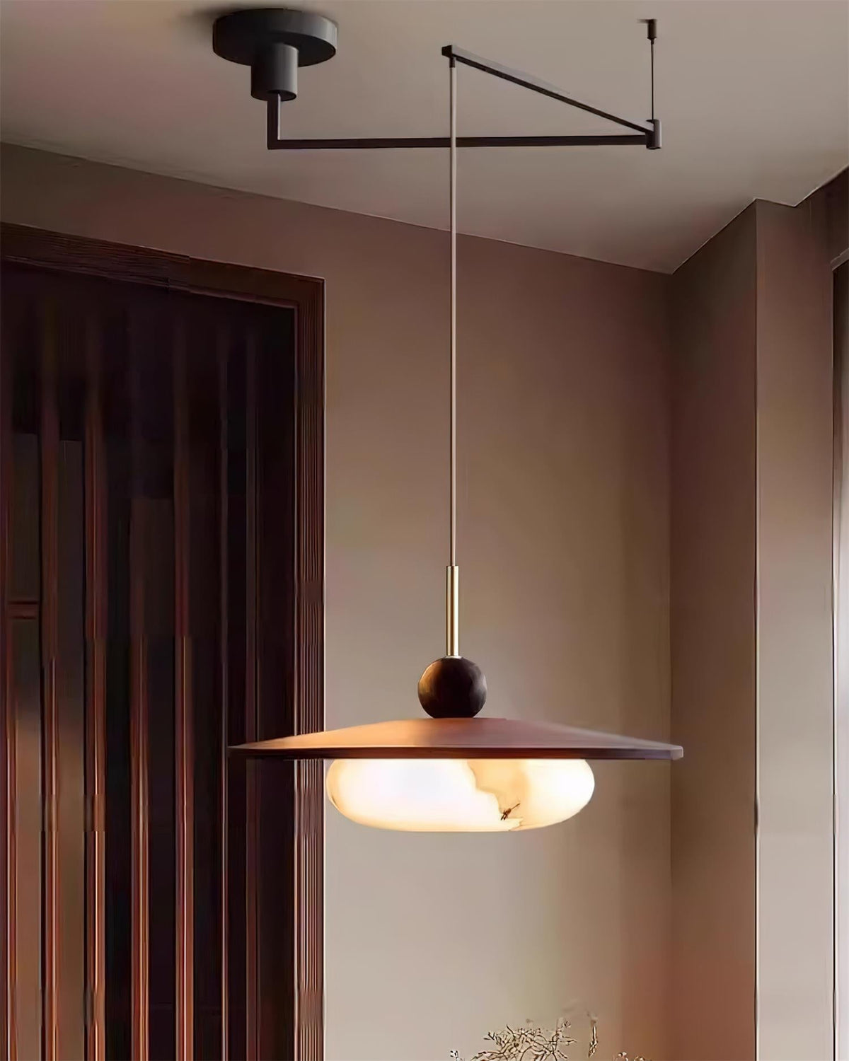 Turlo pendant light in a corner of a room beside a dark timber door, arm reaching out from the ceiling