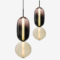 Two Ambero amber glass pendant lights hung at staggered drop heights on a plain background