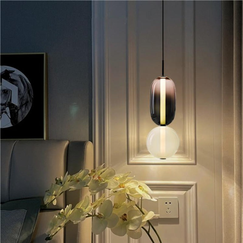 Ambero pendant light lit in a dark blue hallway above a console with orchids