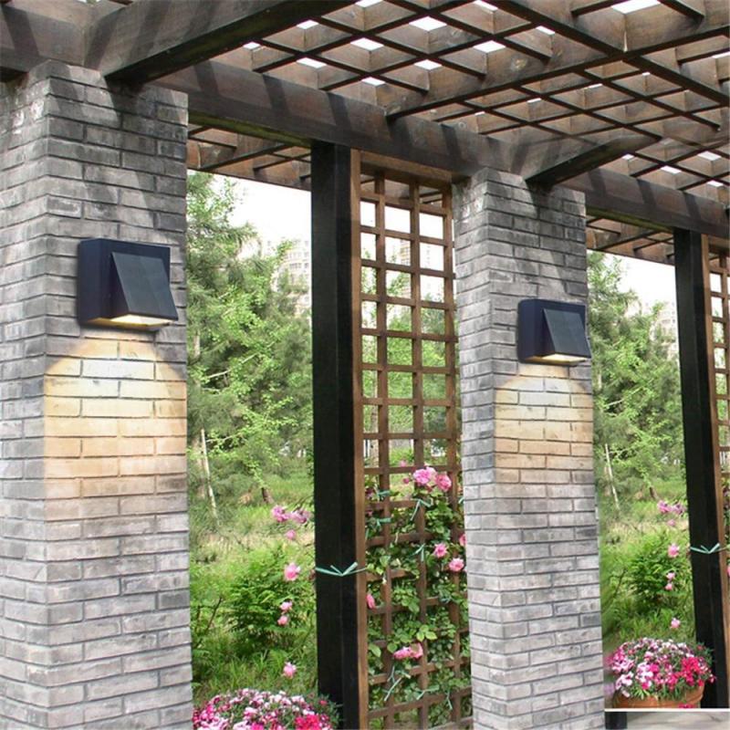 Two Vosto Slim Outdoor Wall Lights on brick pergola pillars in a garden, each washing light down the brickwork