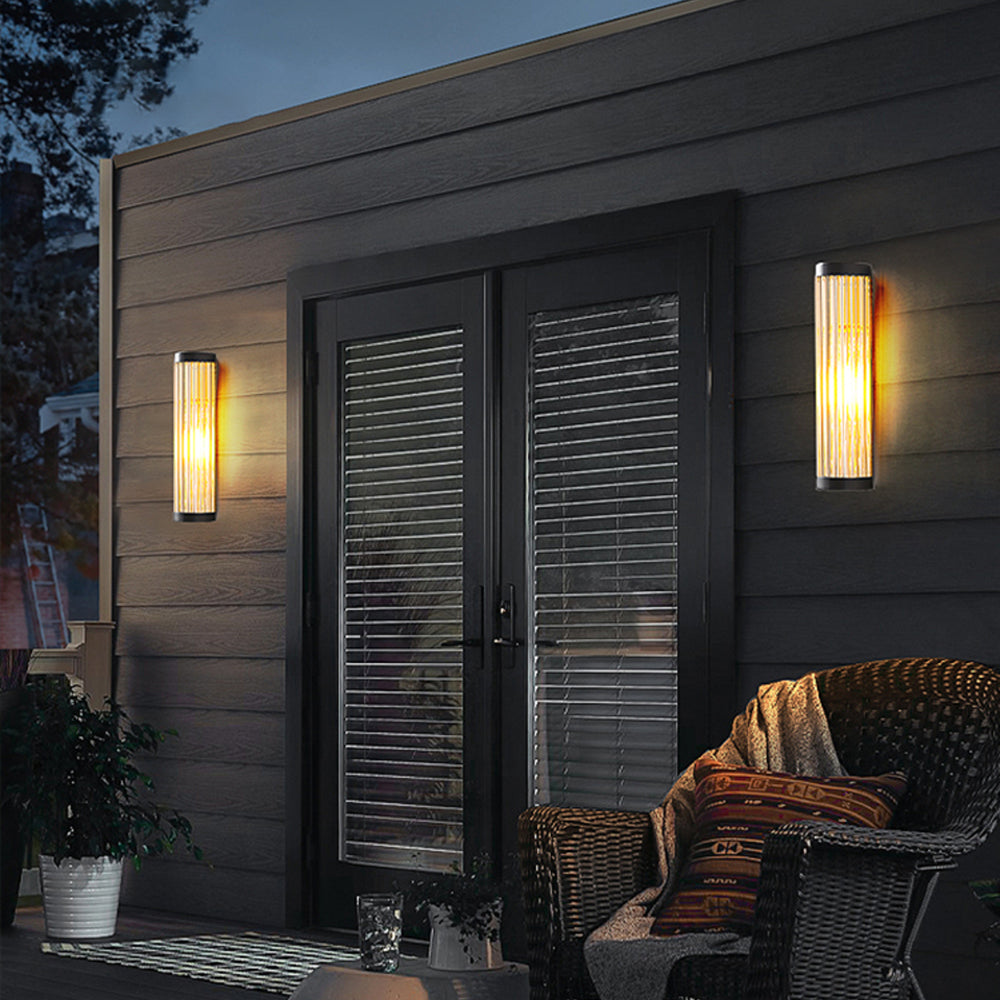 Two Yoro outdoor wall lights mounted on dark timber cladding beside patio doors at dusk