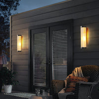 Two Yoro outdoor wall lights mounted on dark timber cladding beside patio doors at dusk