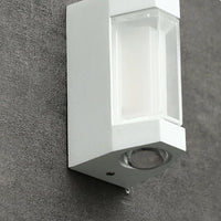 Close view of the white Marvo outdoor wall light on a concrete wall showing the clear lens box and round base lens