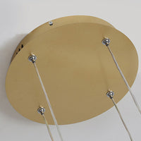 Close view of the round gold ceiling plate and steel suspension wires of the Remo pendant light