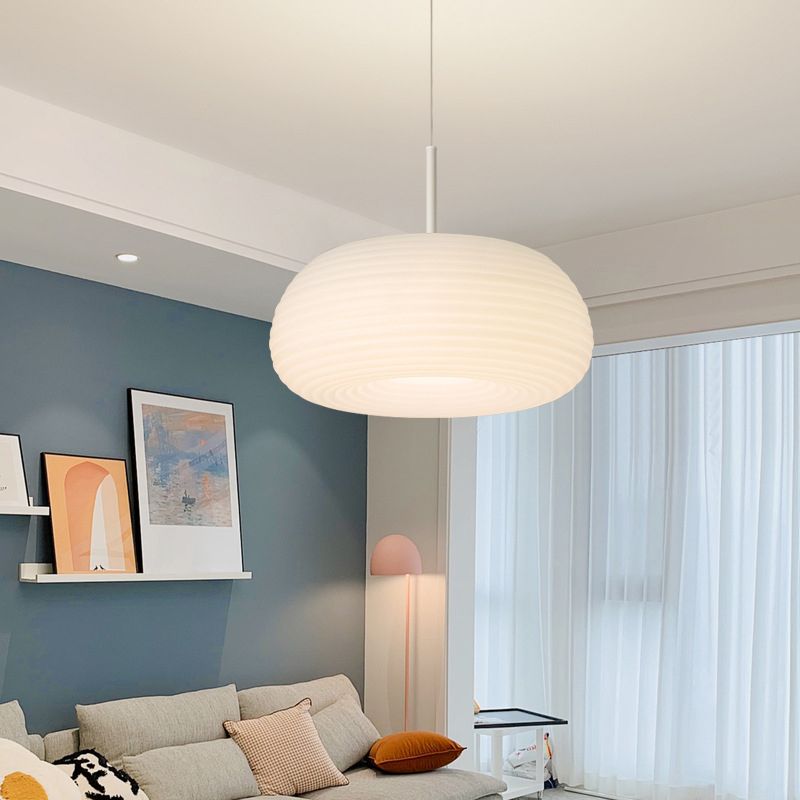 Ombia ribbed pendant hanging in a living room with a blue wall and pale sofa
