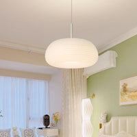 Ombia pendant in a green and cream bedroom, hung above a seating corner