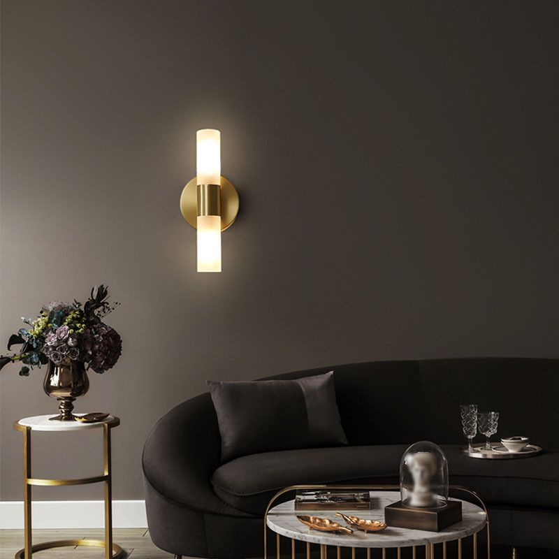 Brenlo twin cylinder wall light lit on a dark wall above a curved sofa