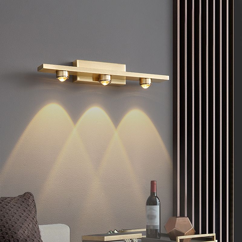 Angled view of the Nolvo brass wall light lit above a living room side table