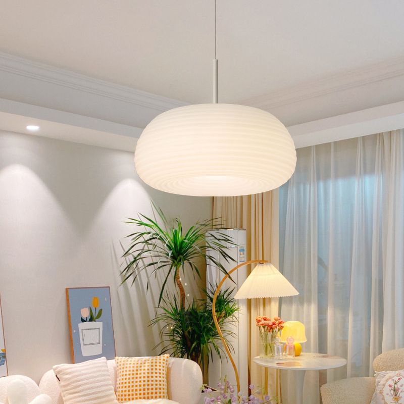 Ombia pendant lit above a living room seating area with plants and sheer curtains