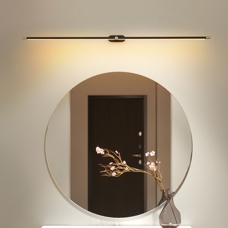 Ivo linear wall light mounted above a round mirror in a hallway, casting warm light