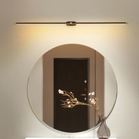 Ivo linear wall light mounted above a round mirror in a hallway, casting warm light