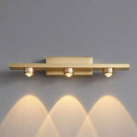 Nolvo brass wall light lit on a grey wall casting three scalloped pools of warm light