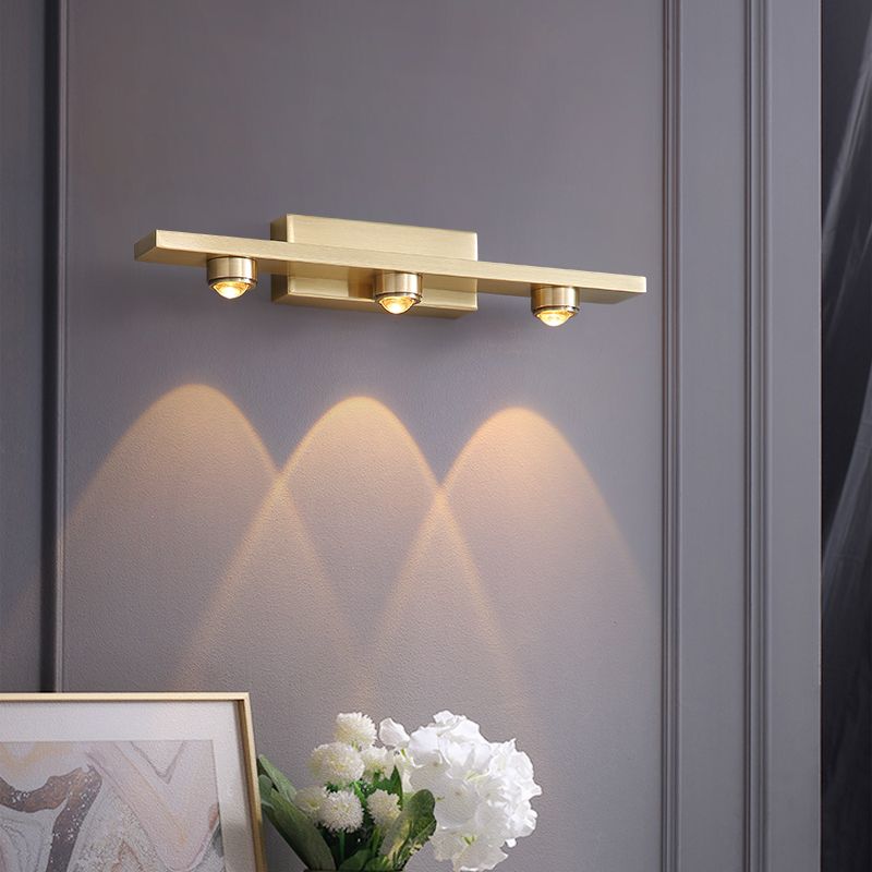 Nolvo brass three light wall bar above a console with framed art and white flowers