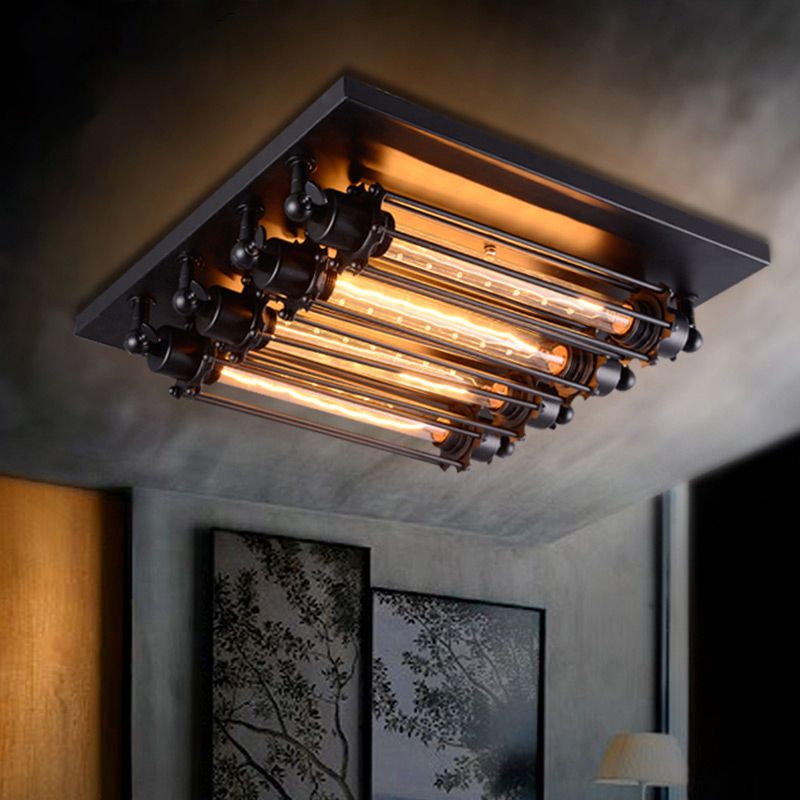 Grindo flush mount ceiling light lit in a grey walled room, showing the warm glow from four filament tubes