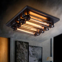 Grindo flush mount ceiling light lit in a grey walled room, showing the warm glow from four filament tubes