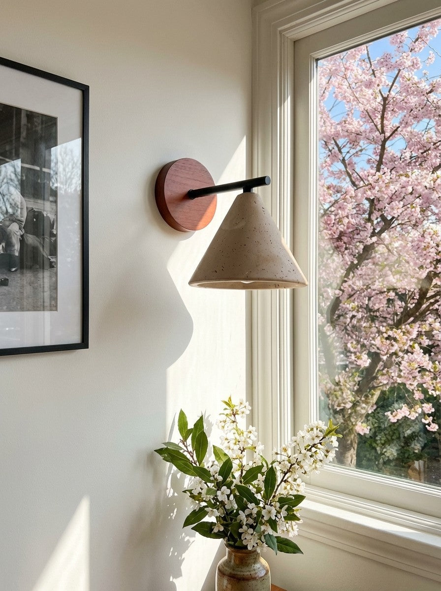 Marlo travertine wall light mounted beside a window with blossom outside