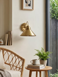 Arvo Bronze Cone Wall Light unlit on a cream wall beside a garden window