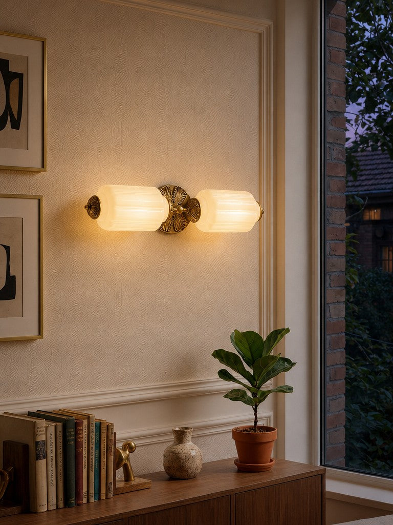 Lanto Horizontal Milk Glass Wall Light lit in the evening, glowing warmly beside a window
