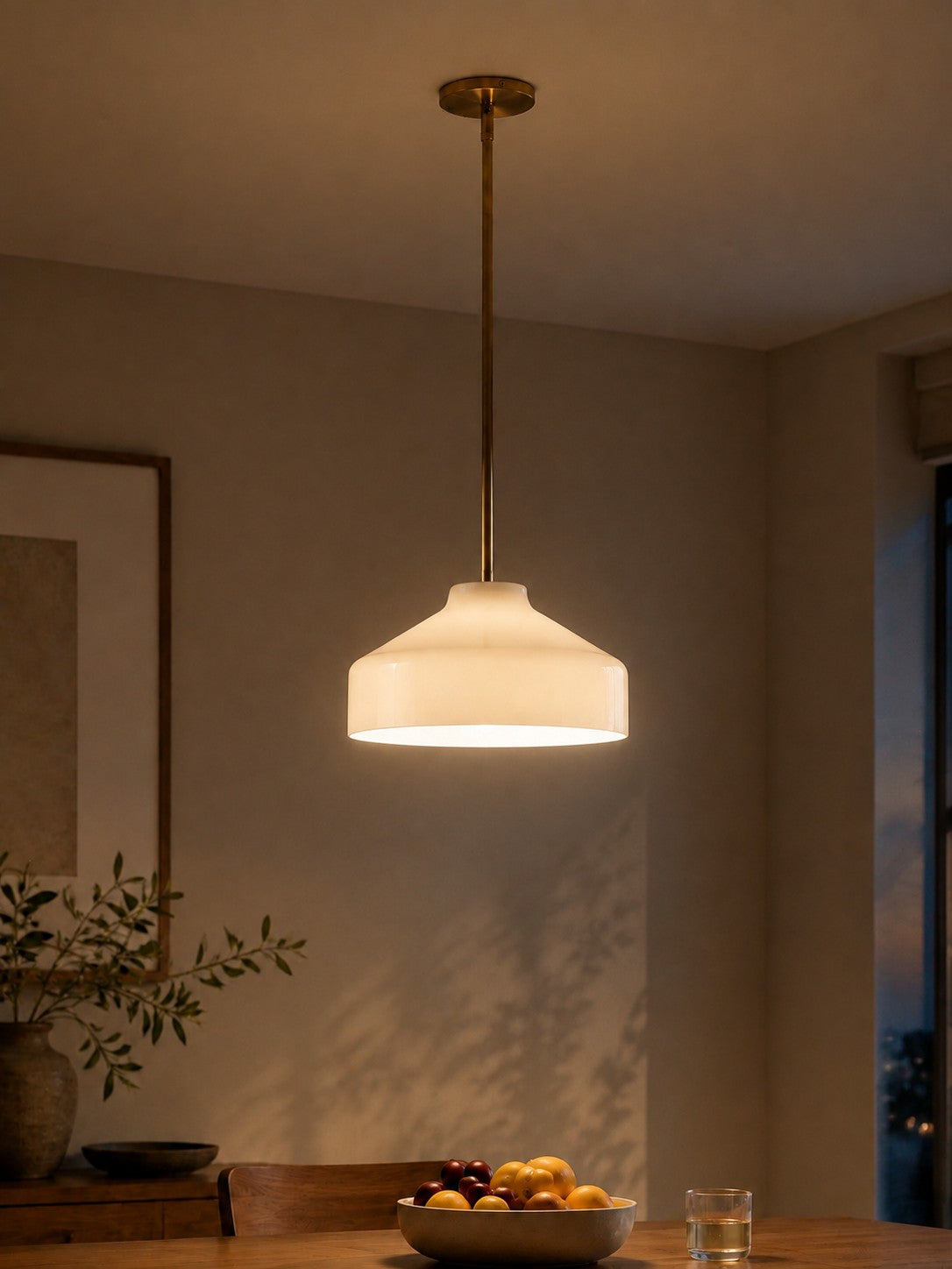 Hano ivory pendant light lit above a dining table in the evening