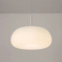 Ombia pendant lit in a neutral white setting, showing the ribbed shade glowing evenly