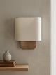 Lino Curved Linen Wall Light in natural linen above a floating oak shelf with books and a vase
