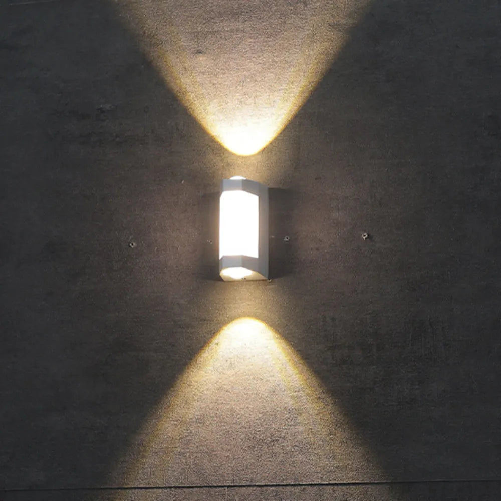 Marvo outdoor wall light lit on a grey concrete wall, throwing symmetrical warm triangles of light up and down