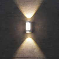 Marvo outdoor wall light lit on a grey concrete wall, throwing symmetrical warm triangles of light up and down