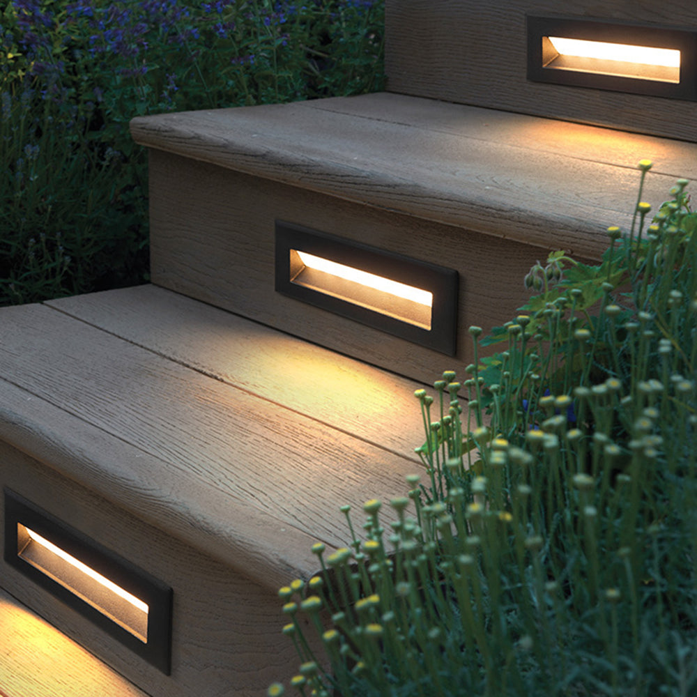 Palo deck step lights glowing warm in timber deck risers with garden planting