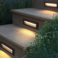 Palo deck step lights glowing warm in timber deck risers with garden planting