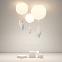 Wisto bear and balloon cluster ceiling light lit in a plain studio room, showing the warm glow of the three shades