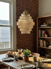 Idra amber ribbed glass pendant hanging over a wooden dining table against exposed brick