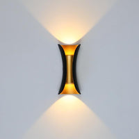 Corva black and gold wall light switched on, throwing one warm cone of light up the wall and one down