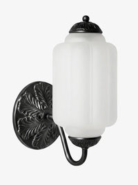 Elva milk glass wall sconce shown from an angle on a plain background