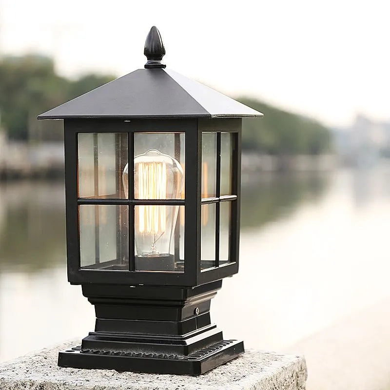 Ashlow outdoor post light mounted on a wall cap outdoors with a warm filament bulb glowing inside