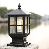Ashlow outdoor post light mounted on a wall cap outdoors with a warm filament bulb glowing inside