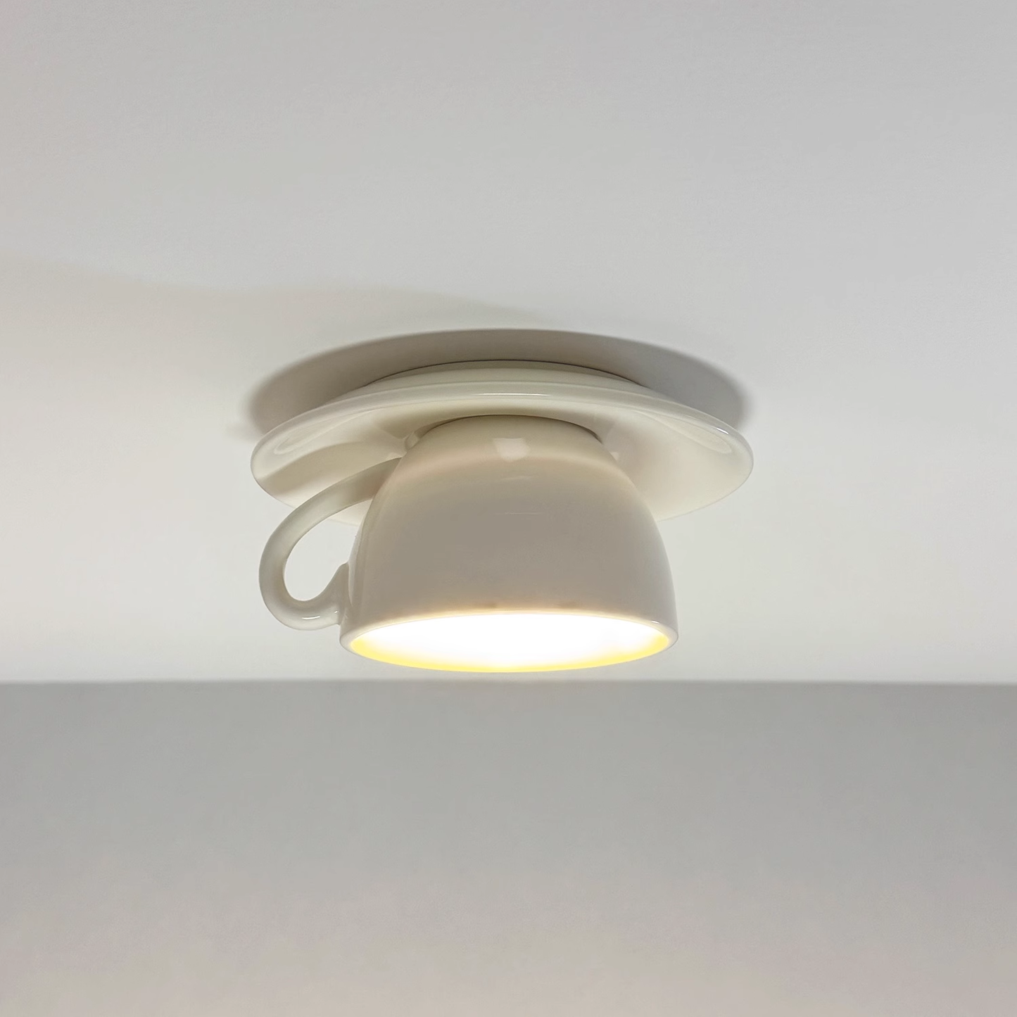 Kupa white ceramic teacup ceiling light switched on with a warm glow from the cup