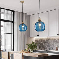 Pair of Riplo blue ripple glass pendant lights lit above a timber kitchen island