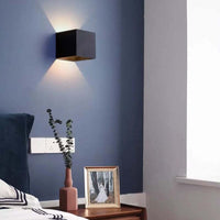 Nexo black wall light casting up and down light on a blue bedroom wall