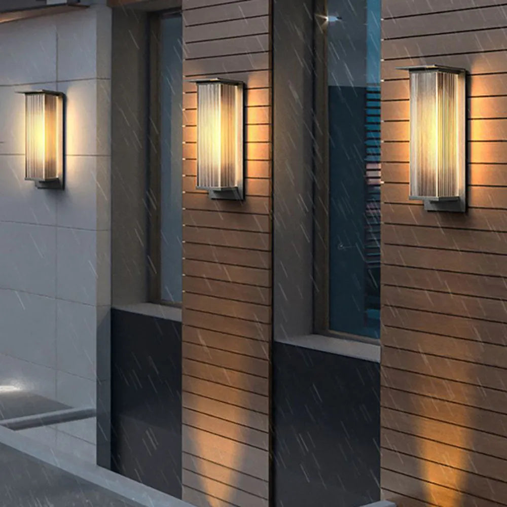 Two Rekta wall lights framing a front door with a potted shrub