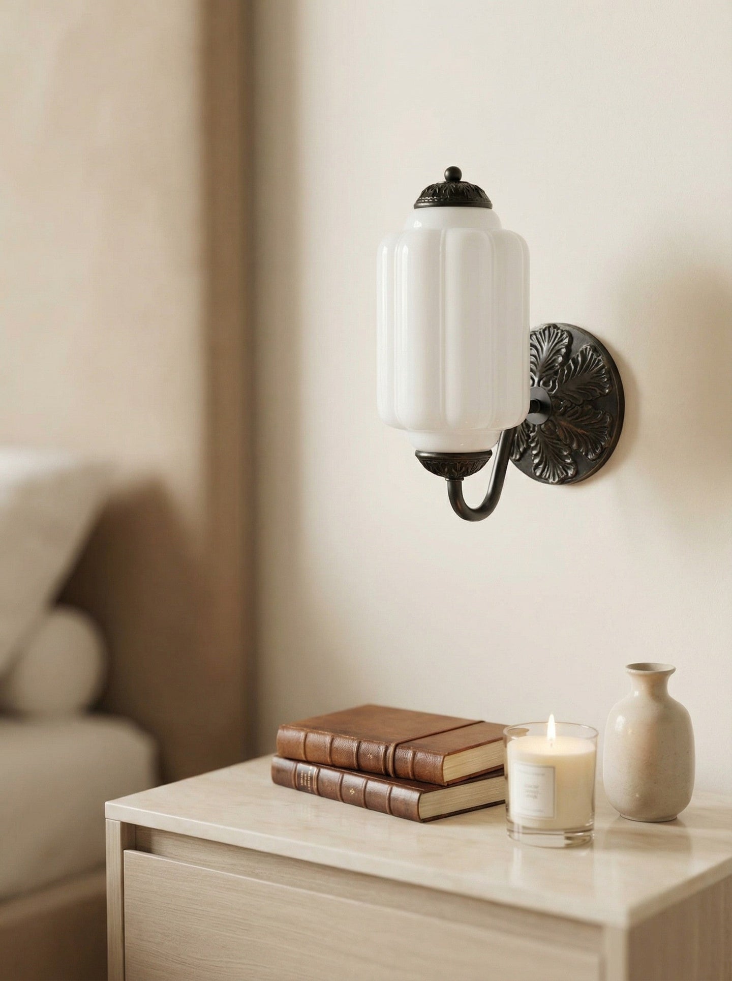 Elva milk glass wall sconce mounted beside a bedside table