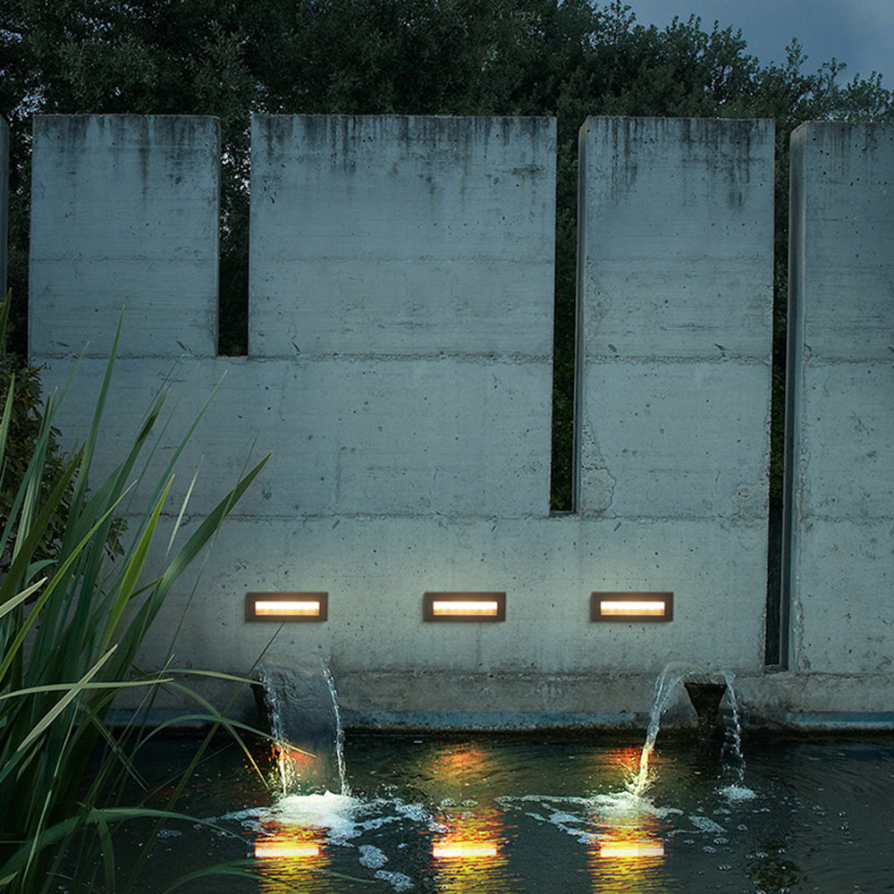 Palo step lights installed in concrete water feature wall above garden pond